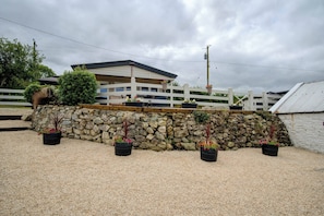 A building with a covered outdoor area, stone wall, and potted plants.