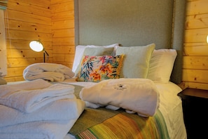 A wooden cabin-style room with a bed, pillows, and a lamp.