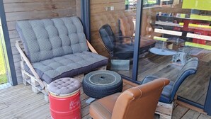 Una terraza de madera con un sofá, sillas y una mesita.