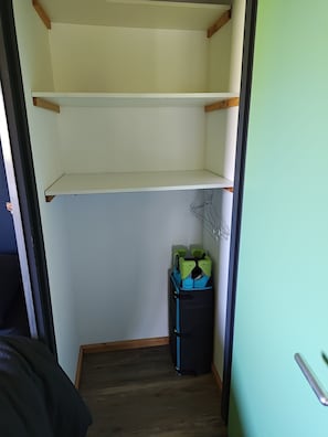Ein Zimmer mit Holzboden, einem schwarzen Koffer und einem Metallgestell.