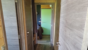 Un pasillo estrecho con paredes de madera y una puerta verde al final.