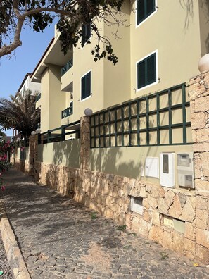A building with stone walls, a paved pathway, and a gate with a ball finial. - Salty Holiday Apartment in The Branco Sea condominium (Santa Maria)