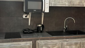 Et køkken med mikrobølgeovn, kaffemaskine og vask.