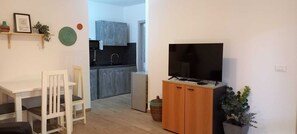 A compact living space with a dining area, a kitchenette, and a TV on a wooden stand. - Salty Holiday Apartment in The Branco Sea condominium (Santa Maria)