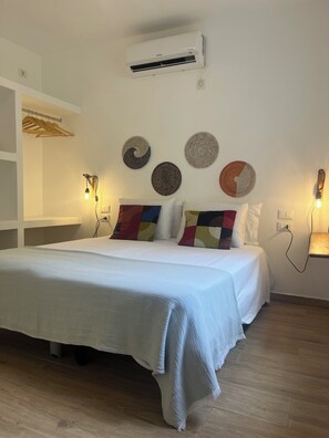 A bedroom with a bed, an air conditioner, wall-mounted lights, and decorative wall art. - Salty Holiday Apartment in The Branco Sea condominium (Santa Maria)