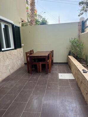 A patio with a wooden table and chairs, stone walls, and a view of the sky. - Salty Holiday Apartment in The Branco Sea condominium (Santa Maria)