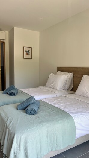 A hotel room with two beds, a wooden headboard, a framed picture on the wall, and rolled towels on the beds. - Pep s Home 2 Villa divided into 2 new homes, quiet location, 10 minutes from the beach. (Cavalaire-sur-Mer)