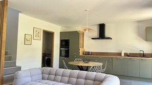 A modern kitchen with a microwave, oven, and a hanging light fixture. - Pep s Home 2 Villa divided into 2 new homes, quiet location, 10 minutes from the beach. (Cavalaire-sur-Mer)