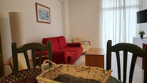 Un salon avec un canapé rouge, une table basse en bois et un téléviseur posé sur un meuble.