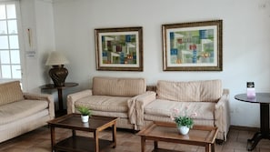 Un salon avec deux canapés, une table basse, une lampe et deux tableaux abstraits accrochés au mur.