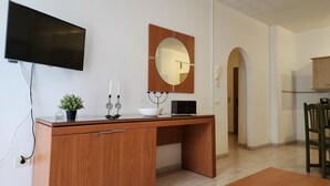 Una scrivania in legno con una televisione a schermo piatto, uno specchio, una ciotola e due candele.