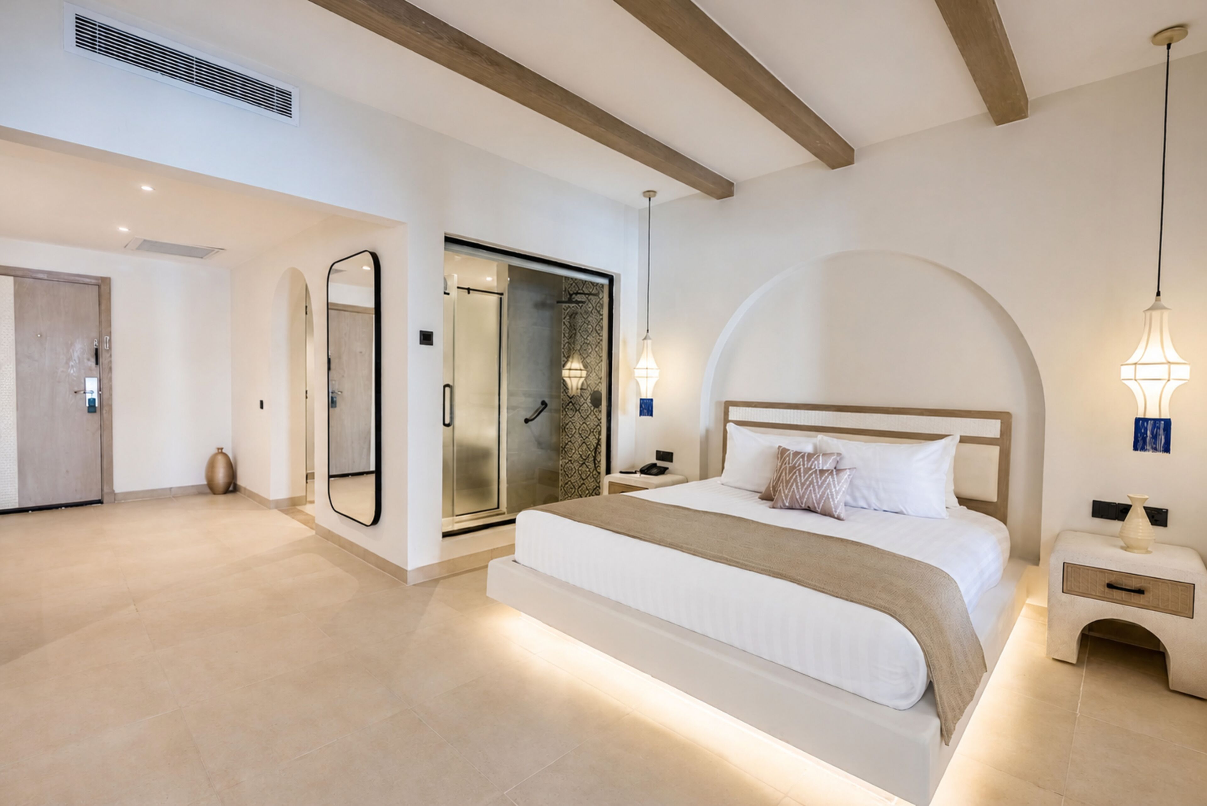 Un dormitorio moderno con una cama grande, un vestidor y un baño con puerta de vidrio.