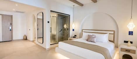 A modern bedroom with a large bed, a walk-in closet, and a bathroom with a glass door.