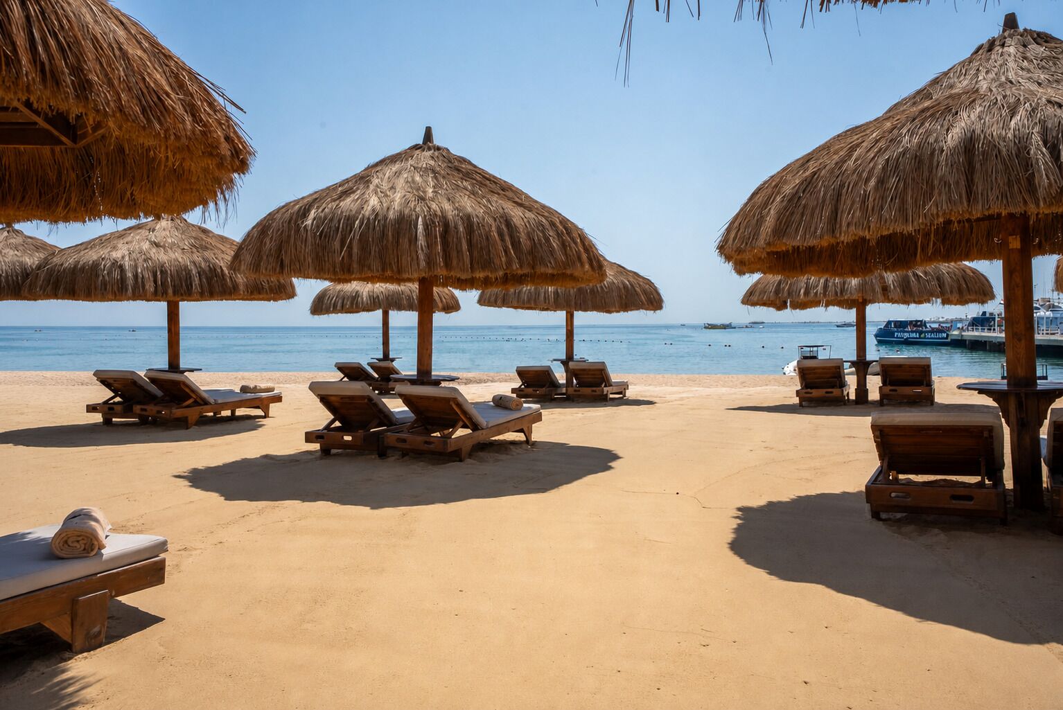 A beach with sun loungers and thatched umbrellas.