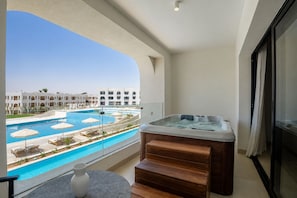 Un balcón con hidromasaje, piscina y vista a un complejo hotelero.