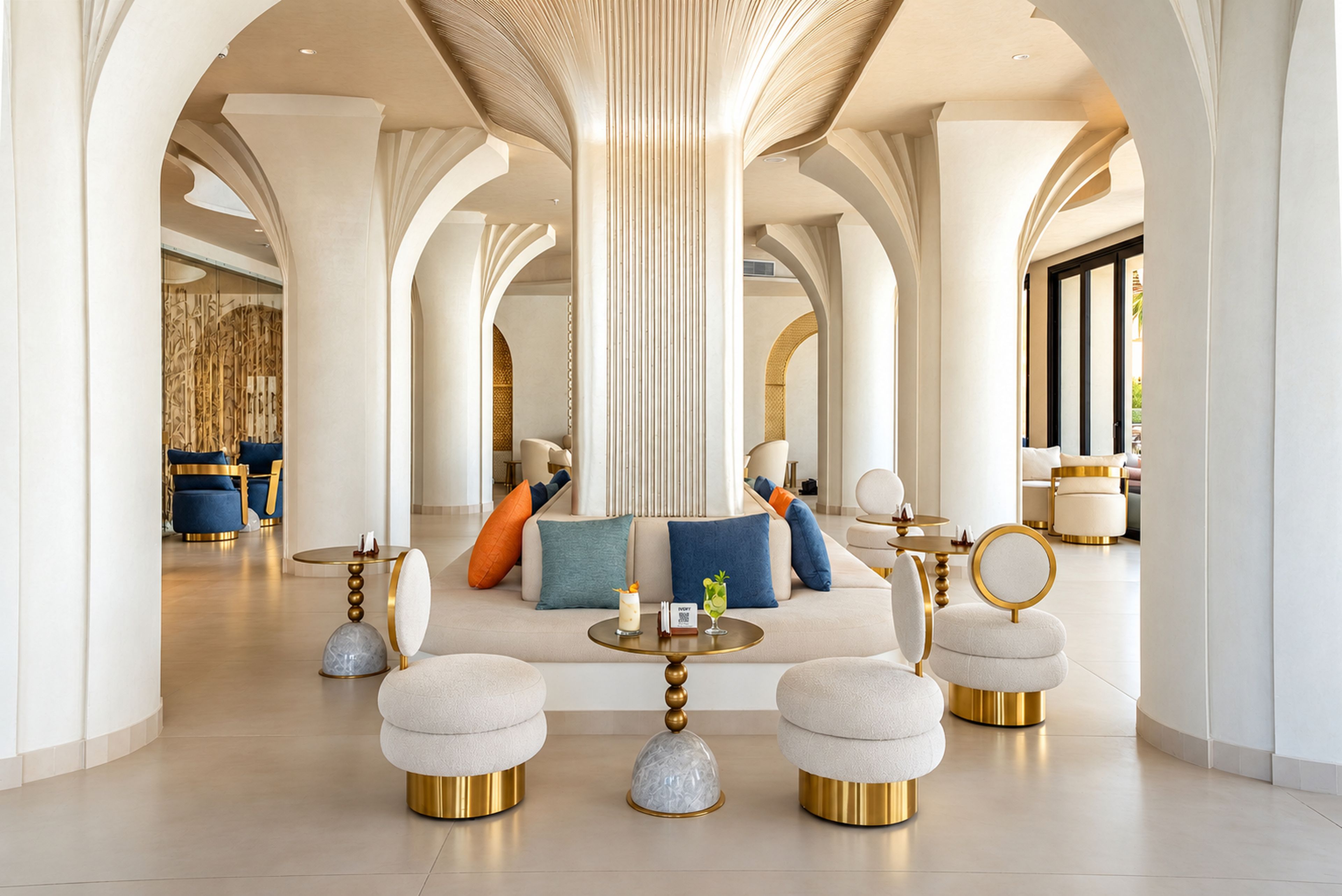 A spacious lobby with high ceilings, a central seating area with sofas and ottomans, and a large column structure.