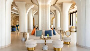 A spacious lobby with high ceilings, a central seating area with sofas and ottomans, and a large column structure.