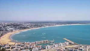 Un paysage urbain côtier avec une plage, un port de plaisance et des immeubles résidentiels.