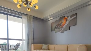 A modern living room with a beige sofa, a round coffee table, and a chandelier. - A piece of Heaven (Nairobi)