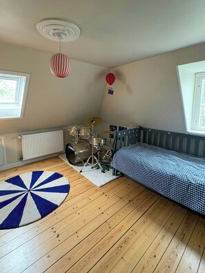 Et værelse med en seng, et trommesæt, en radiator, et vindue og en loftsvifte.