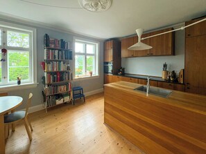 Ett kök med träskåp, en inbyggd ugn, en diskho och ett fönster med utsikt över grönområden.