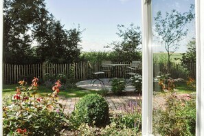 Ein Garten mit Holzzaun, gepflasterter Terrasse und Gartenmöbeln.