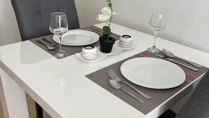 Et spisebord med hvide tallerkener, bestik og en orkidé i potte.