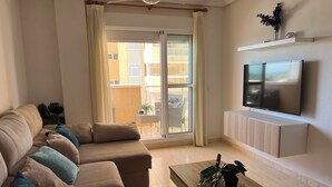 En stue med sofa, sofabord, fjernsyn og en skydedør.