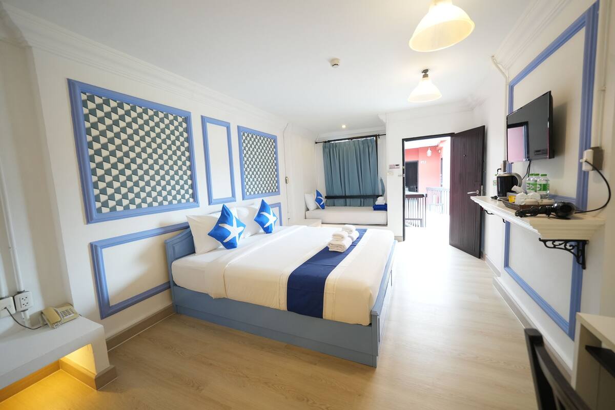 A hotel room with a bed, bedside table, and a TV mounted on the wall.
