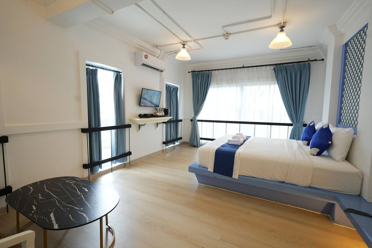 A modern hotel room with a bed, a desk, a chair, and a TV.