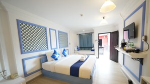 Una habitación de hotel con una cama, un escritorio con teléfono, un televisor y un baño a la vista.