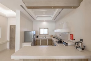 Une cuisine moderne dotée d’un îlot central, d’appareils électroménagers intégrés et d’une fenêtre laissant entrer la lumière naturelle.