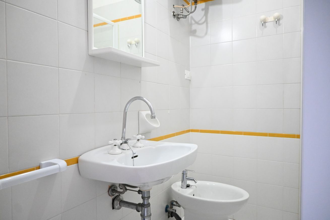 A bathroom with a white sink, a mirror, and a bidet.