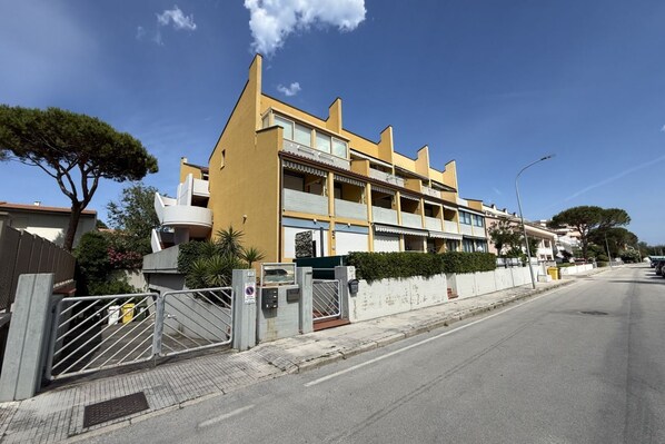 Un immeuble à plusieurs étages doté de balcons, d’une entrée sécurisée et surplombant un ciel dégagé.