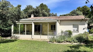Uma casa com alpendre coberto, estufa e jardim.