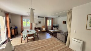 Uma sala de estar com sofá, televisão, mesa de jantar e cadeiras.