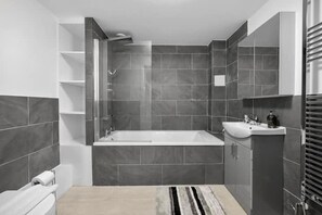 A modern bathroom with a bathtub, a sink, and a shower. - 1 Bed Apartment Sleeps 3 With Balcony (London)