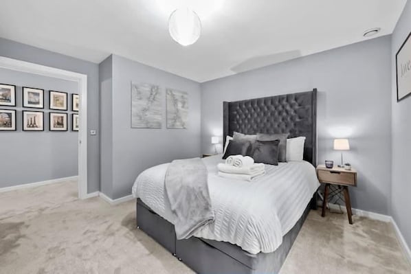 A bedroom with a large bed, a nightstand, a ceiling light, and framed pictures on the wall. - 1 Bed Apartment Sleeps 3 With Balcony (London)