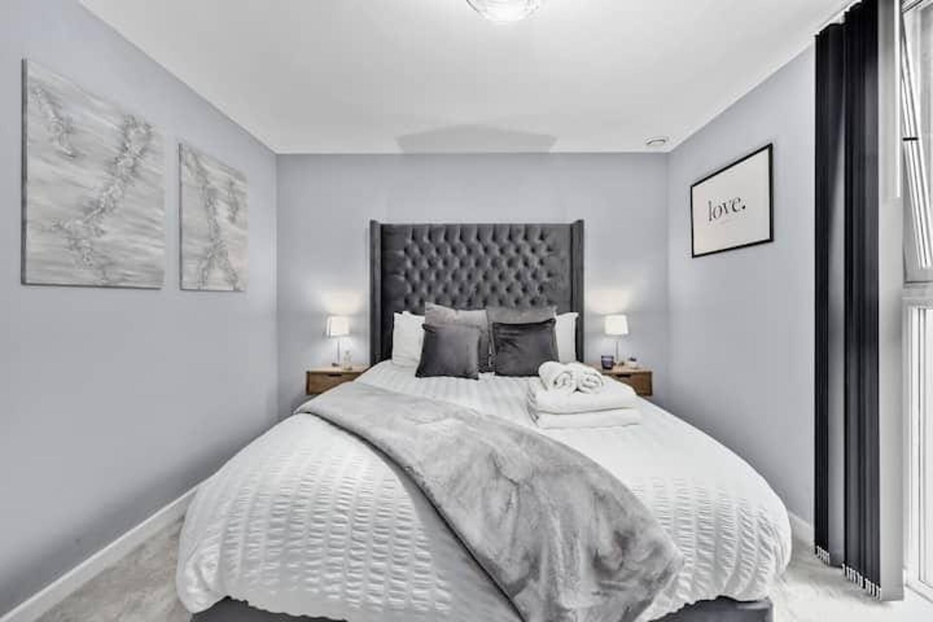 Een keurig opgemaakte slaapkamer met een groot bed, twee nachtkastjes en een hoofdeinde.