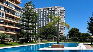 Una piscina con agua cristalina azul, rodeada de césped cuidado y árboles.