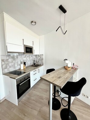 A modern kitchen with white cabinets, a microwave, a sink, and a wooden countertop. - Torremolinos Sky View: The city at your feet. (Torremolinos)
