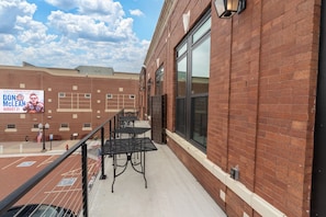 A brick building with a balcony, outdoor seating, and a large billboard.