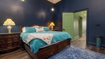 Een slaapkamer met een houten bed, twee bedlampen, een groene deur en een kamerbreed tapijt met een patroon.