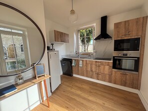A kitchen with wooden cabinets, a refrigerator, a sink, a microwave, and an oven. - Los Arcos | Two renovated houses for 15 people. 4-legged friends too! (Annonay)