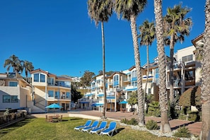 A resort with multiple-story buildings, palm trees, and outdoor seating areas. - Everything You Need for a Perfect Escape! Partial Ocean View, Free Parking! (Avalon)