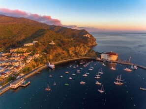 Une ville côtière dotée d’un port de plaisance rempli de bateaux, d’un bâtiment remarquable avec un toit rouge et d’un pont qui relie la ville au continent.