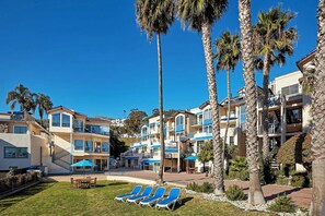 Un resort con edificios de varios pisos, zonas de estar al aire libre y palmeras.