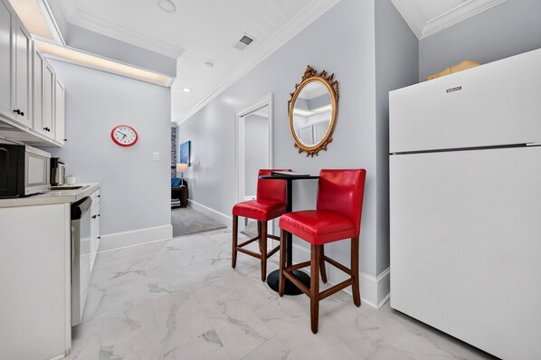 A modern kitchen with white cabinetry, a red-framed mirror, and a white refrigerator.