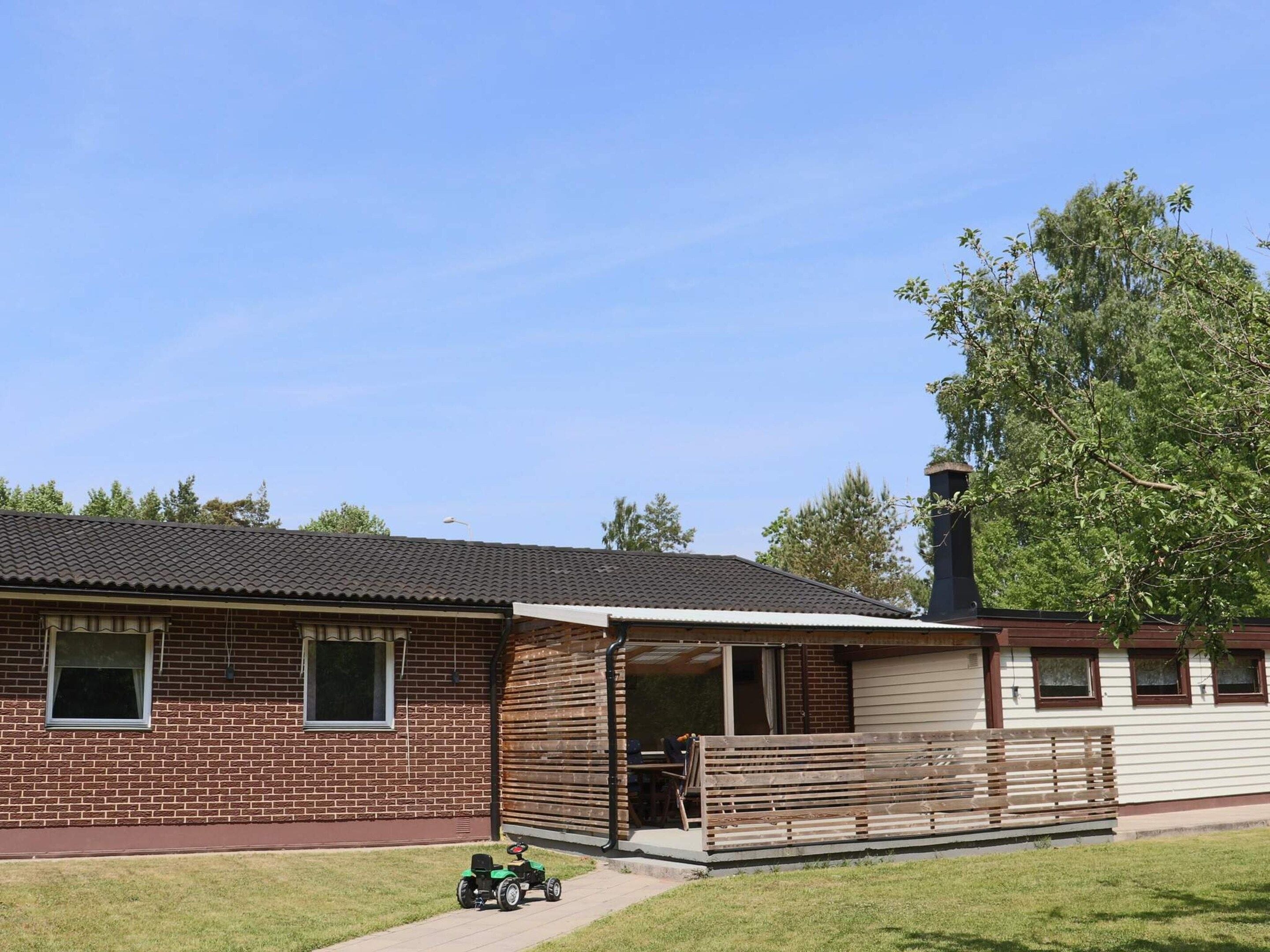 A two-story brick house with a covered patio and a small green vehicle parked outside.