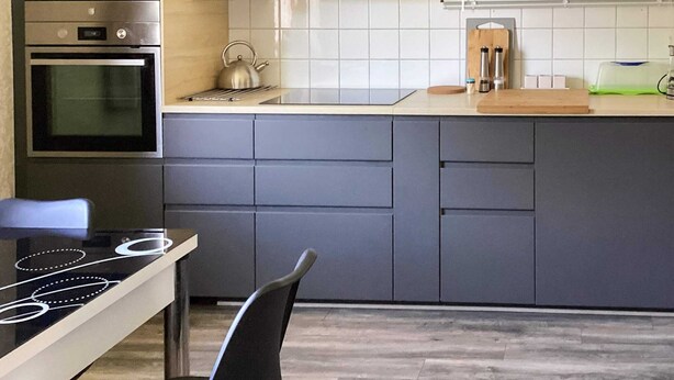 Una cocina moderna con horno integrado, hervidor, pileta y encimera.